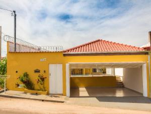 une maison jaune avec un garage dans l'établissement Pouso Oliveira Casa com ar condicionado, à São João Batista do Glória