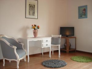 a room with a desk and two chairs and a television at Chambre d'hôtes La Haie Fleurie in Chevillard