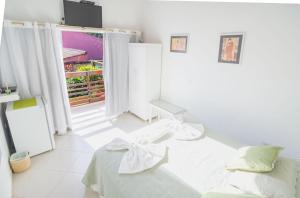 Habitación blanca con cama y puerta abierta en Pousada Irashai, en Juquei