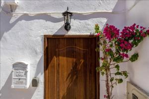 une porte en bois dans un mur blanc avec des fleurs roses dans l'établissement Canary House, à Ingenio