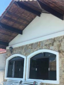 two windows on a house with a wooden roof at No Centro com Piscina Aquecida solar in Peruíbe