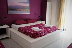 1 dormitorio con 2 camas y pared púrpura en Casa vacanza Civita Catania Centro, en Catania