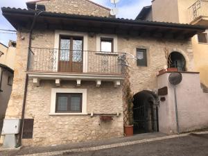 ein Steinhaus mit Balkon auf einer Straße in der Unterkunft IL MIGNOLO DI SAN GIOVANNI in San Demetrio neʼ Vestini