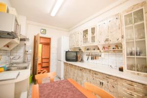 a kitchen with white cabinets and a sink and a television at Apartament Happynest in Predeal