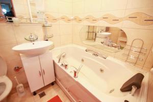 a bathroom with a sink and a bath tub and a sink at Apartament Happynest in Predeal +14 photos