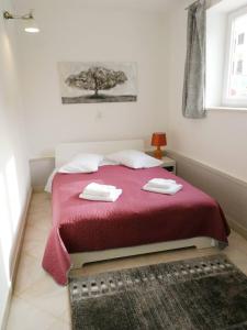 a bedroom with a red bed with two towels on it at Apartman Unka in Metković