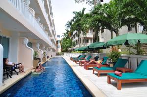 uma piscina do hotel com pessoas sentadas em espreguiçadeiras em Baan Karonburi Resort - SHA Plus em Praia de Karon