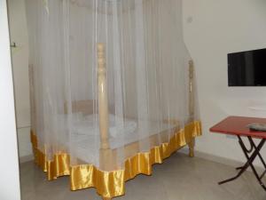 Bett mit gelbem Vorhang in einem Zimmer in der Unterkunft New Kase Guest House Zaana Kampala in Kampala