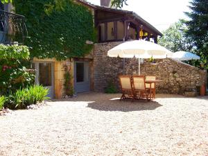 een tafel en stoelen met een parasol voor een gebouw bij Domaine de Cadenne in Saint-Antonin