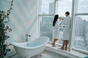 a couple standing next to a bath tub in a window at 65 Hotel, Rothschild Tel Aviv - an Atlas Boutique Hotel in Tel Aviv