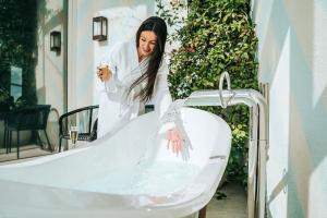 a woman washing her hands in a bathtub at 65 Hotel, Rothschild Tel Aviv - an Atlas Boutique Hotel in Tel Aviv