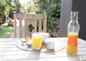 a table with two glasses of orange juice and a bottle at Blue Grass Nest in Nelspruit