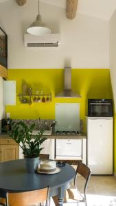 uma cozinha com uma mesa e uma parede amarela em les cerisiers de stella em Blauvac
