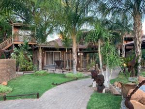 a house with palm trees and a statue in front of it at Country Lodge in Upington