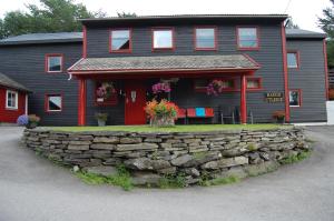 a house with a stone wall in front of it at Haugo Utleige Lodge in Vossevangen
