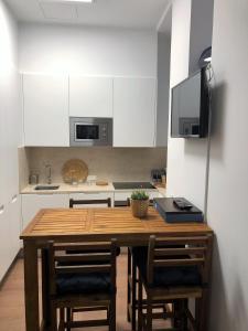 een keuken met een houten tafel met stoelen en een televisie bij Pico da Bica in Lissabon