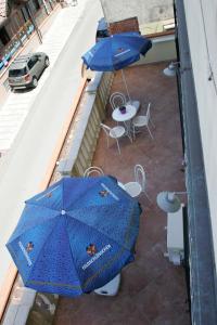 einen Balkon mit zwei blauen Sonnenschirmen, Tischen und Stühlen in der Unterkunft Casa Vacanze Rosy " Nel Centro" in Palinuro