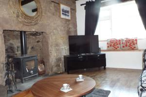 a living room with a table and a fireplace at Turner Cottage in Norham