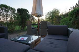 un patio con sofá y mesa con sombrilla en Sylthaus, en Archsum