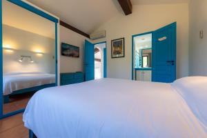 a bedroom with a white bed and blue doors at Résidence Belvedere de Palombaggia in Porto-Vecchio