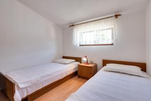2 Betten in einem weißen Zimmer mit Fenster in der Unterkunft Apartments Kronja in Grebaštica