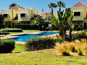 サン・ハビエルにあるRoda Golf Resort Los Alcazaresのスイミングプールと家があるリゾートヤード