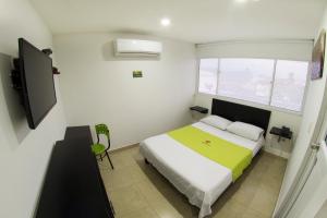 een kleine slaapkamer met een bed en een televisie bij Hotel Embajador del Llano in Villavicencio