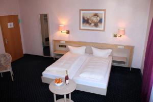 ein Hotelzimmer mit einem Bett und einem Tisch mit einer Flasche Wein in der Unterkunft Hotel Adlerhof in Tauberbischofsheim