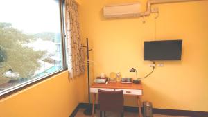 里山旅棧民宿 Li Shan Homestay في فولي: غرفة بها مكتب مع تلفزيون ونافذة
