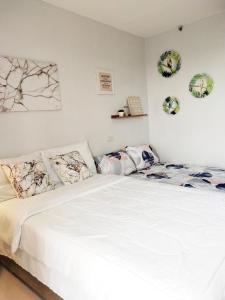 una camera da letto con un grande letto bianco con cuscini di Cloud 907 Cityscapes Condominium a Bacolod