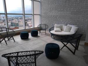 uma sala de estar com um sofá, cadeiras e janelas em Flat Aconchego, próximo ao centro de Osasco, ar condicionado, academia, piscina, wifi e varanda em Osasco
