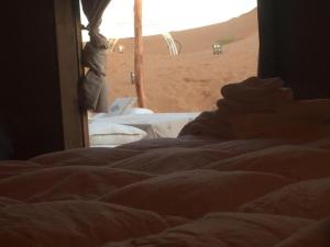 un letto in una stanza con deserto sullo sfondo di Boutchrafine Luxury Camp a Erfoud