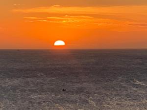una puesta de sol sobre el océano con el sol en el cielo en Praia Grande Arraial Do Cabo, en Arraial do Cabo
