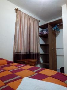 ein Schlafzimmer mit einem Bett und einem Fenster mit einem Vorhang in der Unterkunft Recámara rústica in Mexiko-Stadt