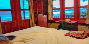 a bedroom with a bed and a table and windows at Dolin Cottage in Hilibotodane