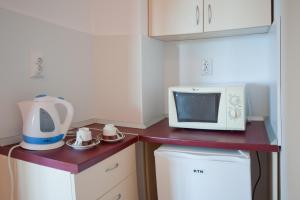 a small kitchen with a microwave and a refrigerator at Stella di Mare Guest House in Ravda
