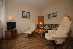 ein Wohnzimmer mit einem Sofa, Stühlen und einem TV in der Unterkunft Strandroggen in Wangerland