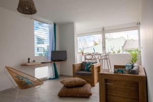 sala de estar con sofá, sillas y ventanas en Beau 3 pièces a la marina des 3 ilets, en Les Trois-Îlets