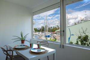 mesa blanca con sillas y ventana con vistas al puerto deportivo en Beau 3 pièces a la marina des 3 ilets, en Les Trois-Îlets