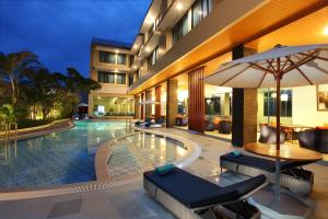a hotel pool with chairs and an umbrella at Swiss-Belhotel Merauke in Merauke