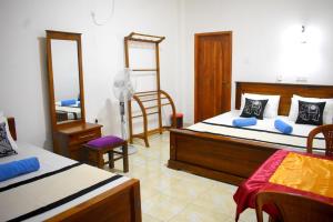 a bedroom with two beds and a mirror at KAUSHIKA RESORT in Anuradhapura