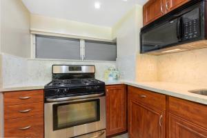 a kitchen with wooden cabinets and a stove top oven at Castle Waikiki Shore Beachfront Condominiums in Honolulu