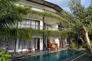 a hotel with a swimming pool in front of a building at Grandpa Guest House in Canggu