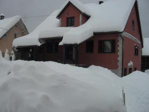 a house covered in snow with a pile at Apartman Anika in Moravice