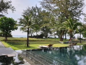 a swimming pool with palm trees in a park at Baan Mai Khao condo in Mai Khao Beach