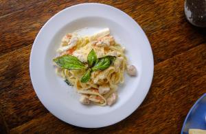 a plate of pasta with shrimp and basil on a table at JM Hotel Kuta Lombok in Kuta Lombok