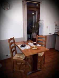 a wooden table with two chairs and a table with food on it at Aux Chambres du Mont in Huisnes-sur-Mer
