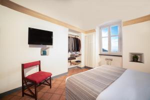 ein Schlafzimmer mit einem Bett, einem Stuhl und einem TV in der Unterkunft Veretiis Home in Borgio Verezzi