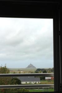 uma vista para uma colina a partir de uma janela em Aux Chambres du Mont em Huisnes-sur-Mer