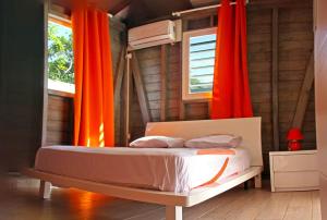 um quarto com cortinas laranja e uma cama num quarto em Beau Bungalow a Port-Louis em Port-Louis